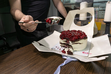 A man eats a cake with a cherry with a spoon. Overeating problem. Social food problem