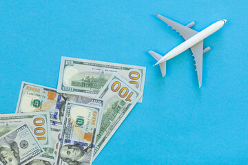 Toy airplane and dollar bills on blue background, flat design. Vacation, air travel and air tickets...