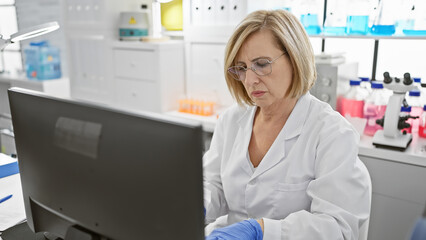 A focused middle-aged woman scientist works on a computer in a modern laboratory setup