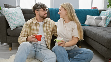 A woman and man, engaging warmly over coffee, exhibit comfort and affection in their cozy living...