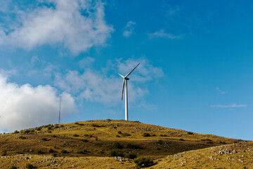 Mountain panorama with turbines of a wind farm producing clean and sustainable electricity helping the environment and the earth.  Green ecological power energy generation. Wind farm eco field