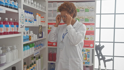African american woman pharmacist adjusting glasses indoors at pharmacy store