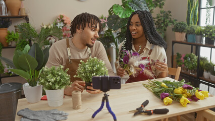A man and a woman arrange flowers in a plant-filled flower shop, recording a video with a...