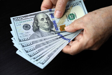 US dollars in wrinkled hands of elderly woman. Concept of pension payments, savings at retirement,...