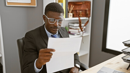 An african american man in a suit examining a document in a modern office