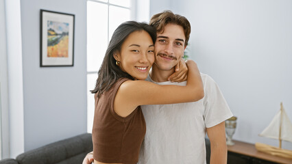 An interracial couple hugs lovingly in a cozy living room, showcasing harmony and affection.