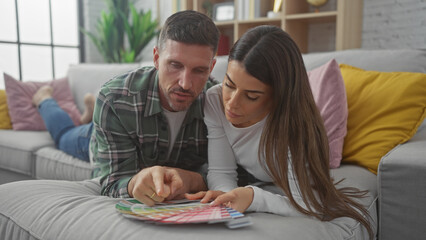 A loving couple examines color swatches on a sofa, reflecting planning and togetherness in their...