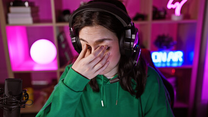 Young woman in a dark gaming room feeling tired or stressed during the night.