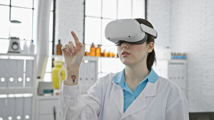A young caucasian woman in a lab coat uses vr technology indoors at a modern laboratory.