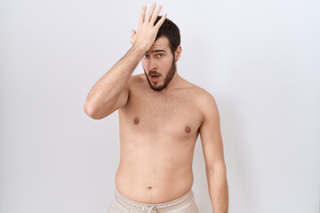 Young hispanic man standing shirtless over white background surprised with hand on head for mistake, remember error. forgot, bad memory concept.