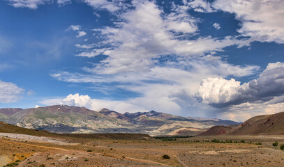 Fototapeta premium red and green mountains under white large clouds