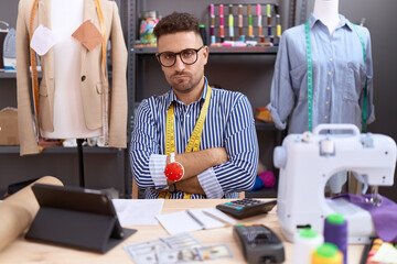 Hispanic man with beard dressmaker designer working at atelier skeptic and nervous, disapproving...