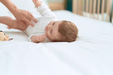 Adorable toddler smiling confident lying on bed with doll at bedroom