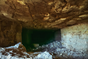 In the underground quarry, the walls and the arched arch of the entrance are lined with stones....