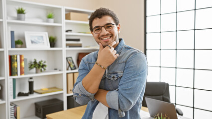 Confident young man with glasses and beard smiling in modern office environment. © Krakenimages.com