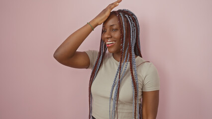 African american woman with braids smiling against a pink isolated background, exuding beauty and...