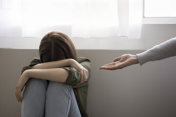Adult woman giving helping hand to crying teenager girl, victim of bullying, abuse, violence,...