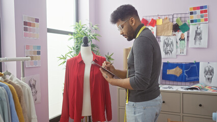 An adult african american man tailoring in a well-lit design room with colorful fabric swatches and...