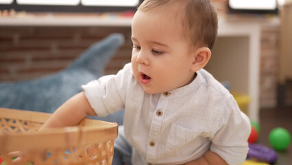 Adorable toddler holding ball of wicker basket at kindergarten