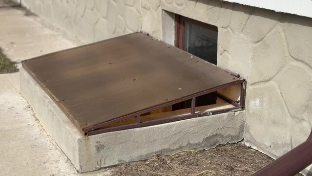 Basement opens in the building of house has window is located below ground level. Window is covered with plexiglass sheet to protect basement from precipitation during rain
