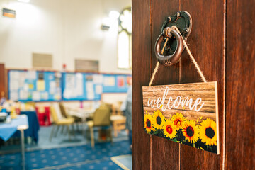 Shallow focus of a homemade and painted Welcome sign seen attached to an English church heavy...
