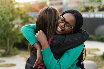 African woman embracing girl with love and emotion - Two happy female best friends hugging each...
