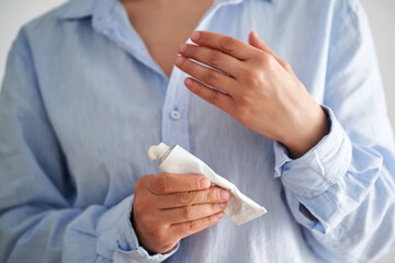 Hands in a blue shirt hold a tube of cream.