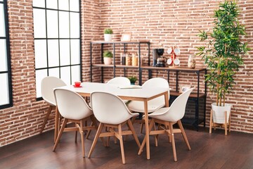 Modern dining room with stylish furniture, large windows, and exposed brick walls exuding urban loft ambiance.