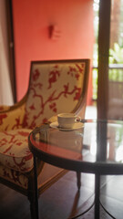 Cozy lounge interior with a stylish armchair, coffee cup on a glass table, and warm ambient lighting.