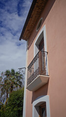 A quaint mediterranean-style balcony with intricate ironwork set against a clear blue sky.
