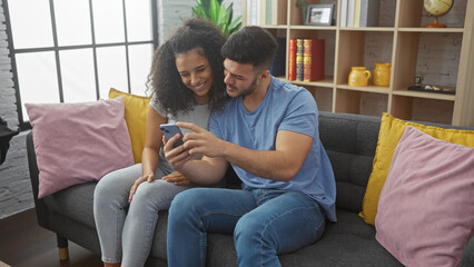 A loving couple enjoys time together looking at a smartphone in their cozy, well-lit living room