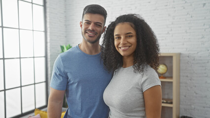 A smiling couple stands together in a bright living room, exuding love and companionship in a cozy...