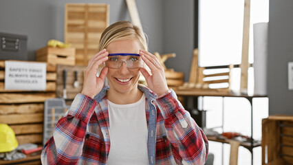 Smiling young woman wearing safety glasses in a woodworking workshop