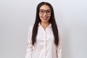 Young arab woman wearing glasses over white background looking positive and happy standing and...