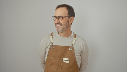 A smiling middle-aged man with a beard wearing glasses and a brown apron against a white background