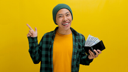 An enthusiastic young Asian man, dressed in a beanie hat and casual shirt, points to an empty space...
