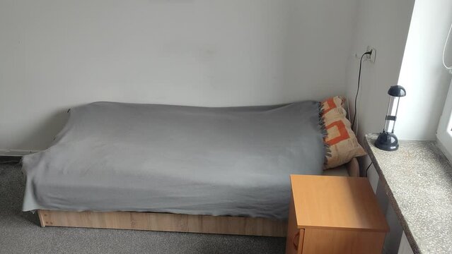 Bed and room in a student dormitory or inexpensive hostel. Minimalistic room interior