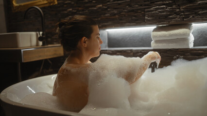 A young woman enjoys a relaxing bubble bath in a luxurious home bathroom.