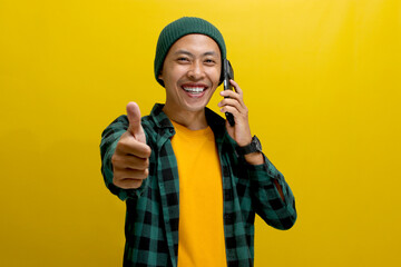 Happy Asian man, wearing a beanie hat and casual shirt, smiles and gives a thumbs up while engaged...