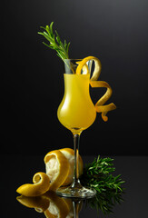 Traditional Italian liqueur Limoncello with rosemary twig on a black background.