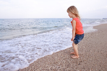 Happy baby girl on the sea in the summer on the nature