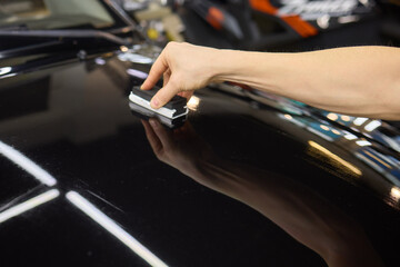 man wearing black gloves applying ceramic coating to car using sponge. Professional car detailing