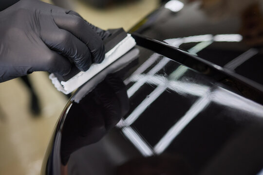 man wearing black gloves applying ceramic coating to car using sponge. Professional car detailing