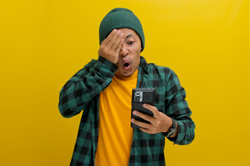 Shocked Asian man, dressed in a beanie hat and casual shirt, covers his eyes in a comical and...