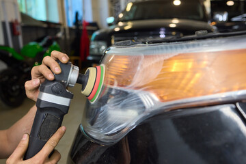 Person using a machine to polish automotive lighting on a car headlight