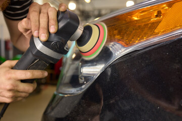 Obraz premium Person using a machine to polish automotive lighting on a car headlight