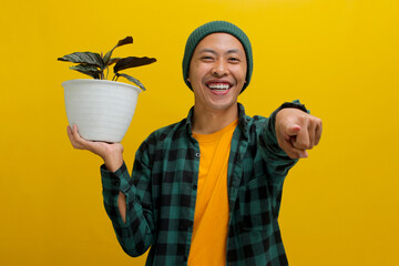 Asian man in a beanie and casual clothes points at the camera with a smile, holding a healthy...