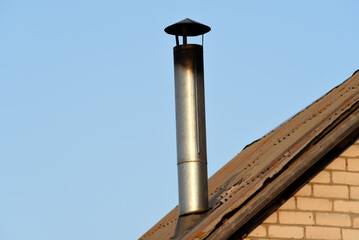 A chimney on a blue sky background. A shiny iron chimney.
