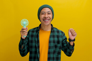 A young Asian man, dressed in a beanie hat and casual shirt, holds a handheld portable electric...