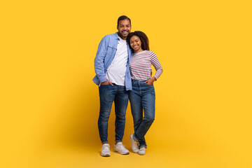 African American lovers are positioned next to each other, standing upright and facing forward, isolated on yellow studio background